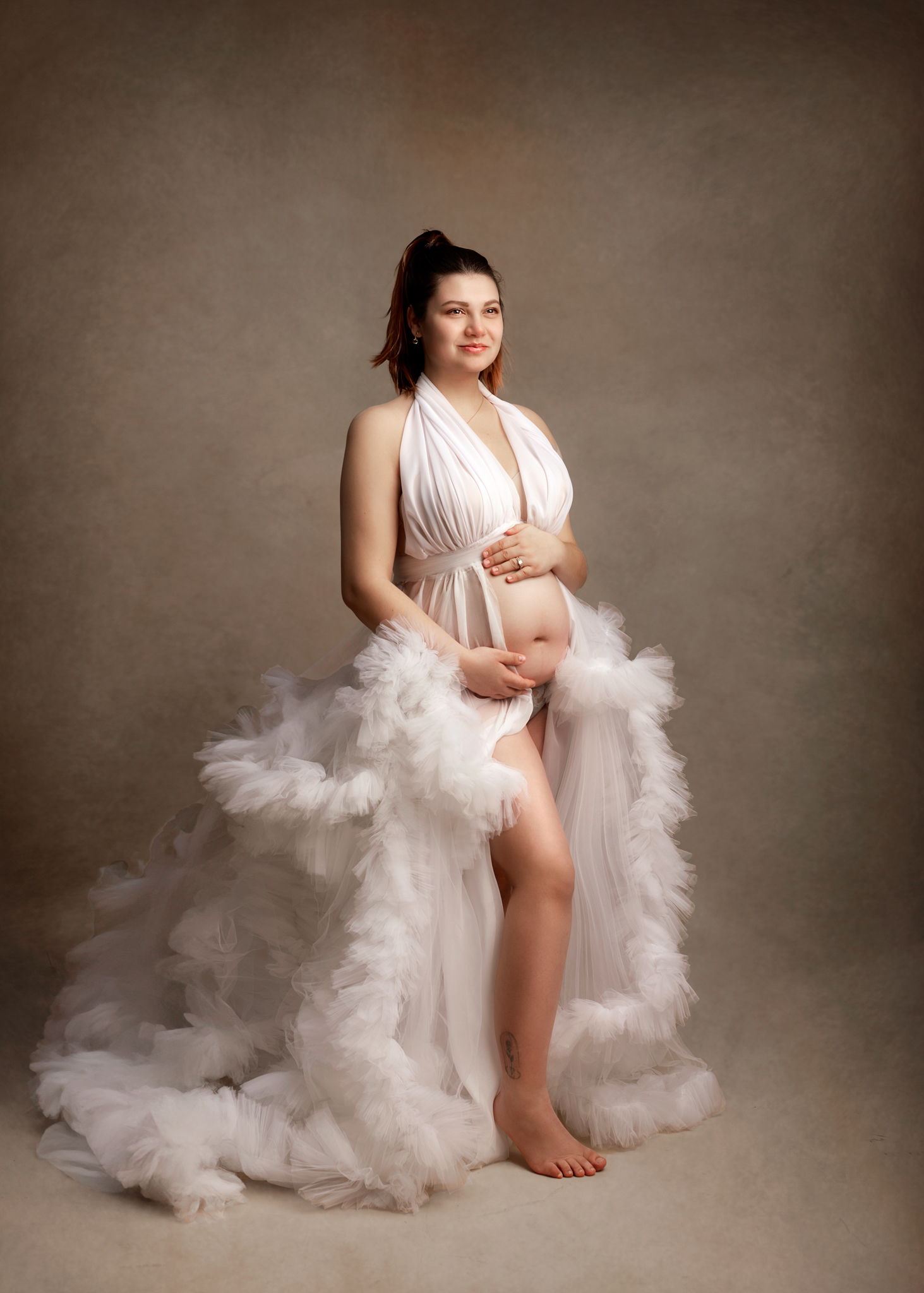 Elegant studio maternity portrait in a white gown