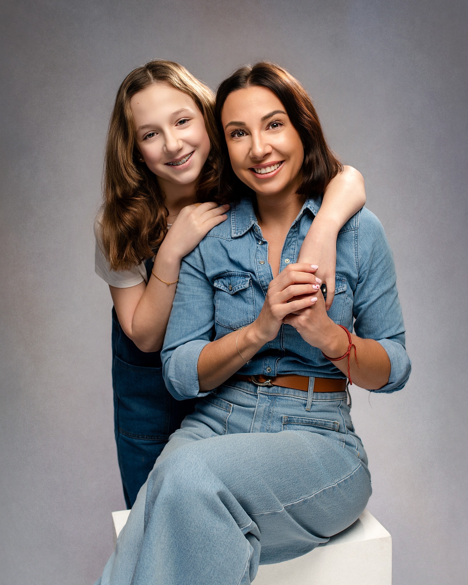 Mother and daughter smiling together in a contemporary studio portrait