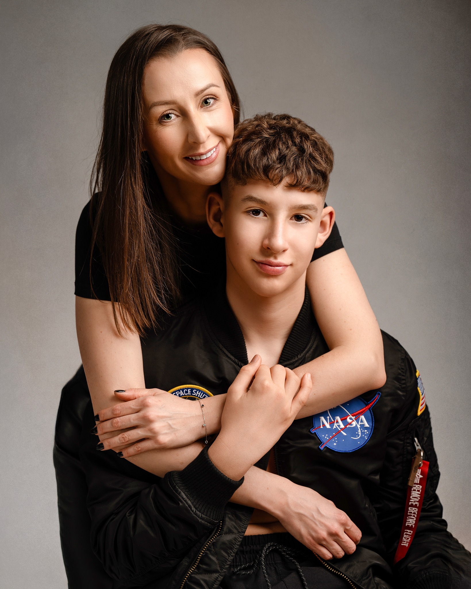 Mother embracing her teenage son in a studio portrait