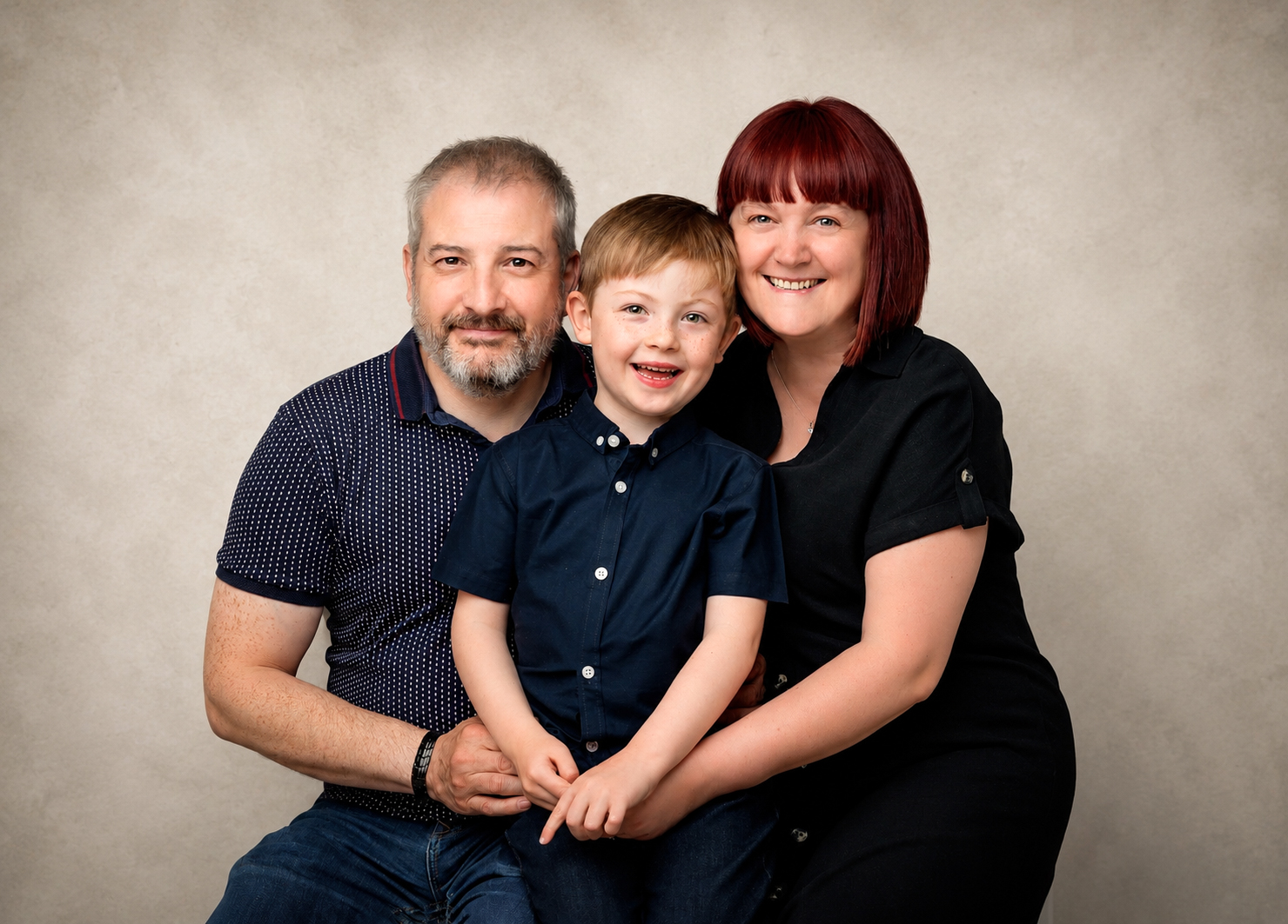 Relaxed studio family portrait with parents and young son