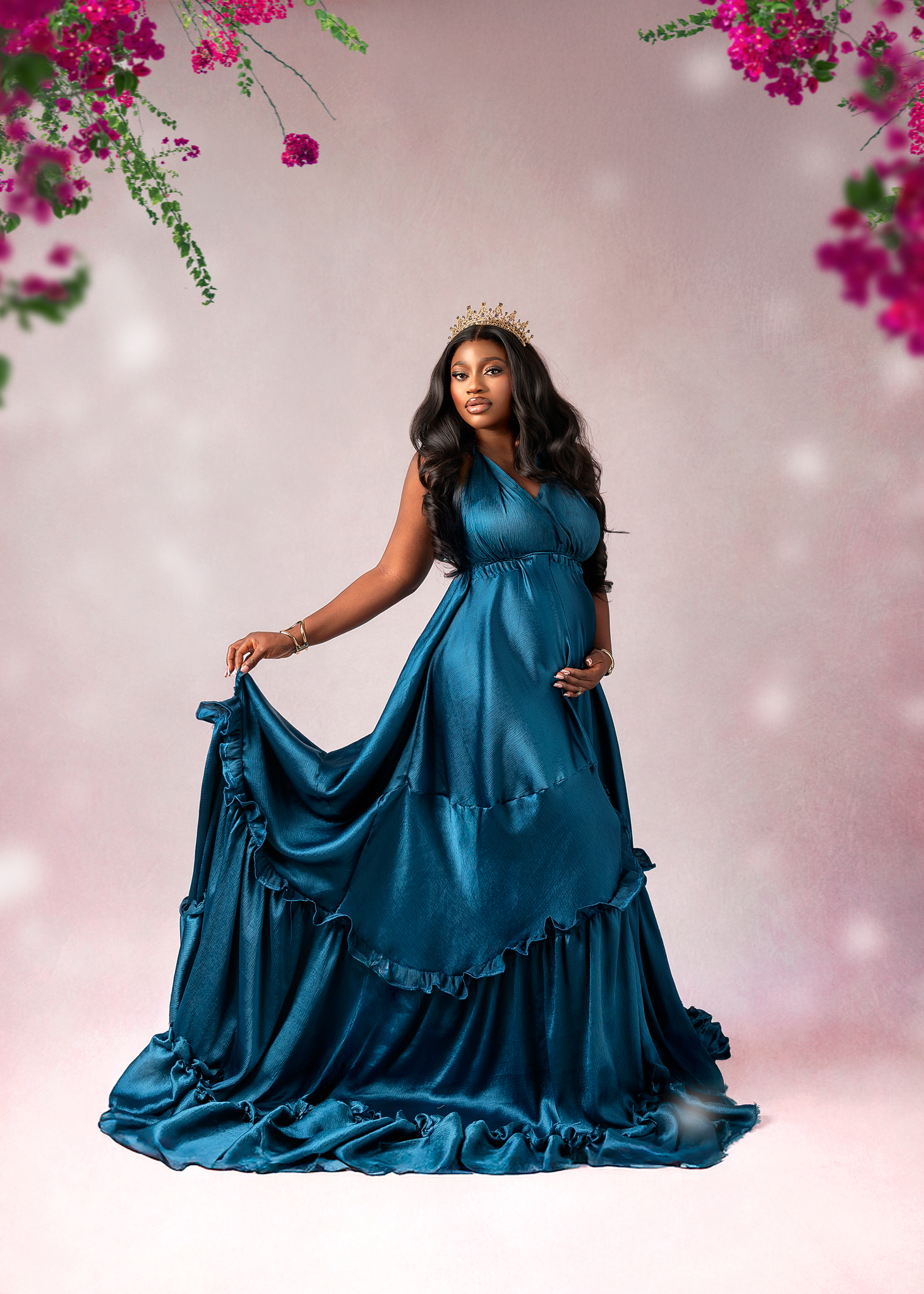 Maternity portrait in a flowing blue gown with floral backdrop
