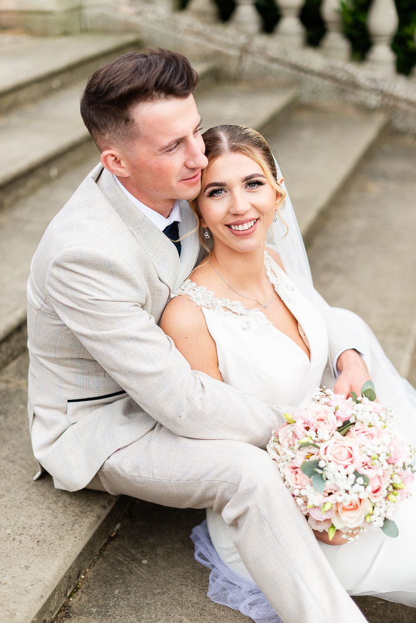 Bride and groom wedding portrait seated on stone steps
